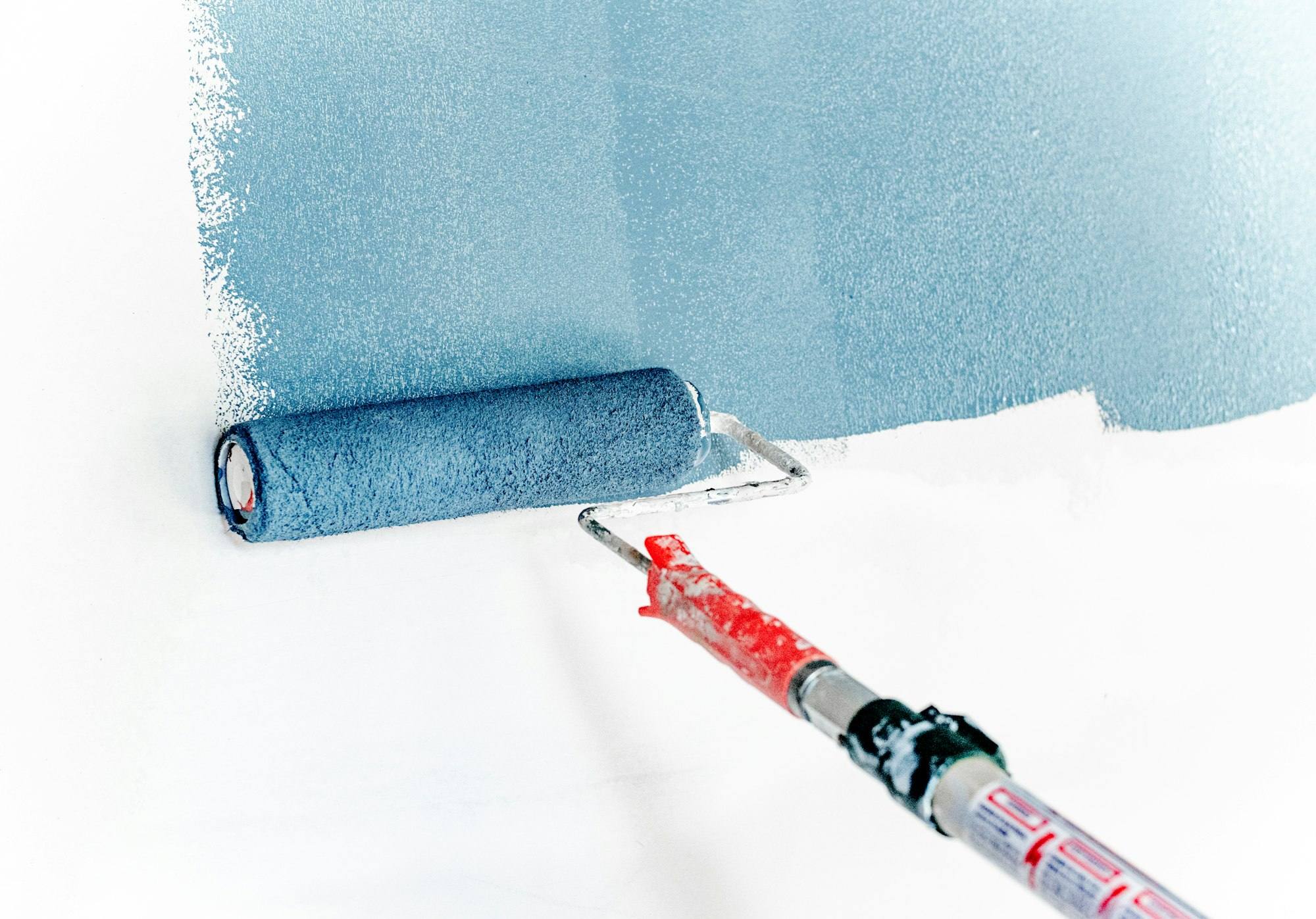 Painter rolling fresh slate-blue paint onto a clean white wall — Jet Painting & Decorating, London