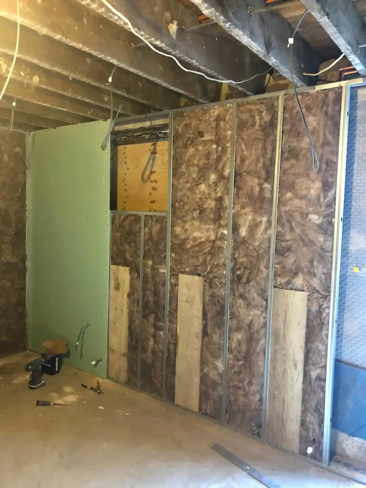 Metal stud-wall frame with mineral wool insulation and a sheet of green moisture-resistant plasterboard installed, plasterboard work by Jet Painting