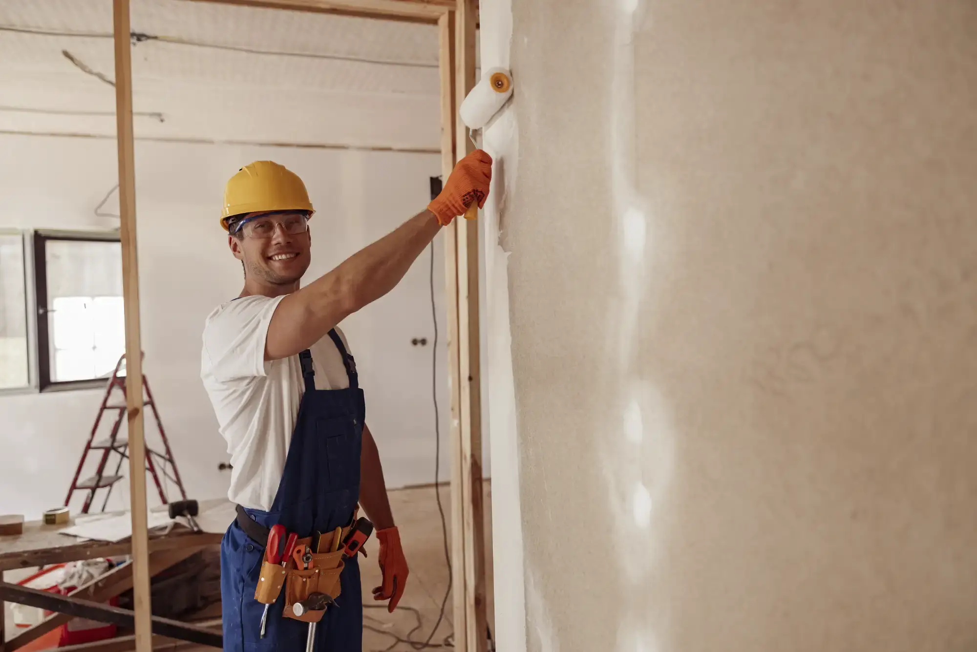 Jet Painting decorator in safety gear smoothing fresh paint onto an interior wall